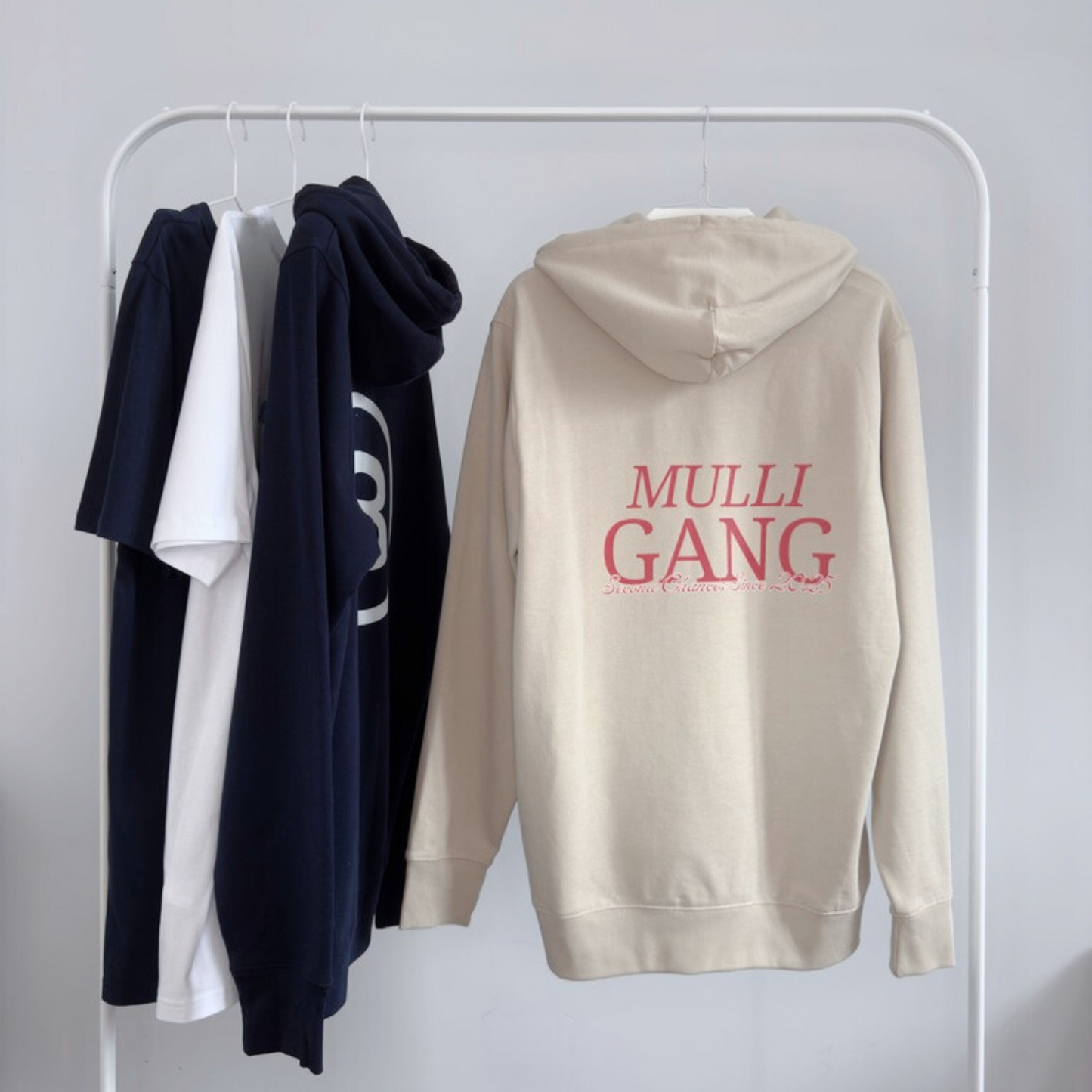 Sand hoodie with maroon Mulligang back print hanging on a wardrobe rail